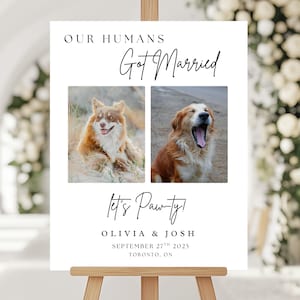 May include: A white wedding sign on a wooden easel with the text "OUR HUMANS Got Married" and "Let's Pawty!". Two photos of dogs are featured. The sign also includes the names Olivia & Josh and the date September 27th, 2025, Toronto, ON.