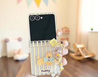 May include: A clear phone case with a yellow and white striped design, featuring a cartoon puppy with a blue bone and the word "Puppy". The case has a decorative strap with yellow charms.
