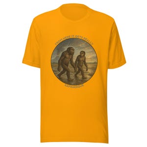 May include: Mustard yellow t-shirt with a circular graphic featuring two hominids walking on a beach. The graphic includes the text "FROM HERE IT GETS REALLY" and "KAFKAESQUE" in a semi-circle.