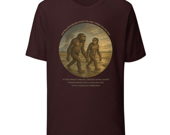 May include: A maroon t-shirt featuring a circular illustration of two ape-like figures walking on a sandy surface. The illustration is framed by text that reads "AUSTRALOPITHECINE STORYTELLING, THREE MILLION BCE". Additional text is below the illustration.