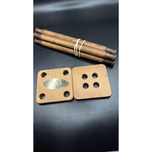 May include: Wooden game pieces, including four dowels bound with a rubber band and two square wooden pieces with holes. One square piece has a metal label that reads "SWISS ROLLER, INC."