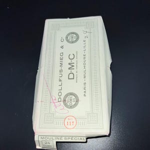May include: A package of DMC brand embroidery floss. The packaging is white with green and black text, including "DMC" and "MOULINE SPÉCIAL". The package has a red sticker with the number "117".