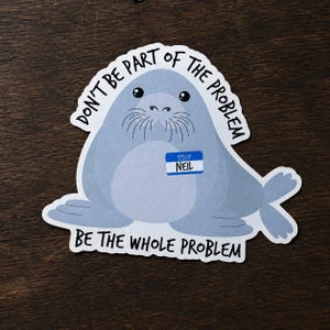 May include: A die-cut sticker featuring a light blue seal with whiskers and a blue name tag that reads HELLO MY NAME IS NEIL. The text DON'T BE PART OF THE PROBLEM is arched above the seal, and BE THE WHOLE PROBLEM is printed below in black.