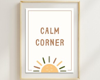 May include: A framed print with the words "CALM CORNER" in brown letters. Below the text is a smiling sun illustration with a light orange face and colorful rays. The frame is a light wood color.