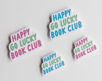 Könnte beinhalten: Vier Aufkleber mit dem Text "HAPPY GO LUCKY BOOK CLUB" in einer verspielten Schriftart. Der Text ist in Rosa, Grün und Blau gehalten und hat eine weiße Umrandung. Die Aufkleber befinden sich auf weißem Hintergrund.
