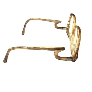 May include: A pair of tortoise shell eyeglasses with round lenses and a unique, curved temple design.