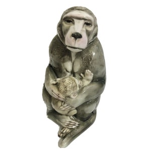 May include: A ceramic sculpture of a gray monkey holding a smaller gray monkey in its arms. The larger monkey has a pink face and a serious expression.