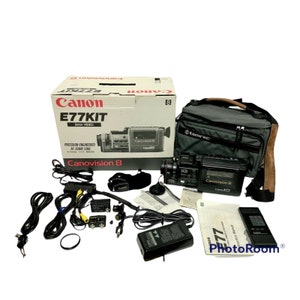 May include: A black Canon E77KIT 8mm video camera with a zoom lens, a black and gray carrying case, and a variety of accessories, including a remote control, cables, and a microphone.