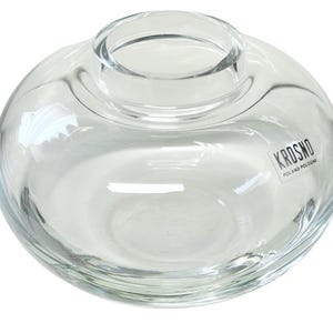 May include: Clear glass vase with a rounded shape and a wide opening. The vase has a label that reads "Krosno Poland Poland".