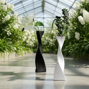 May include: Two modern, twisted ceramic vases, one black and one white, each holding flowers. The vases have a unique, sculptural design. The background features a greenhouse with lush greenery and white flowers, creating a serene and elegant aesthetic.