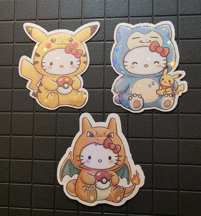 Pode incluir: Tr&ecirc;s autocolantes hologr&aacute;ficos com Hello Kitty vestida como personagens Pok&eacute;mon. Um &eacute; Pikachu, outro &eacute; Snorlax com um Pikachu a dormir, e o terceiro &eacute; Charizard. Cada autocolante segura uma Pok&eacute; Bola e tem um la&ccedil;o vermelho.