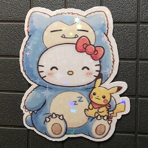 Pode incluir: Um autocolante hologr&aacute;fico com uma personagem de desenho animado vestida de Snorlax, com um la&ccedil;o vermelho. Um pequeno Pikachu tamb&eacute;m est&aacute; presente. O autocolante tem um esquema de cores azul e branco com detalhes brilhantes.