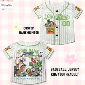 May include: A white baseball jersey with thin green pinstripes, featuring Toy Story character graphics on the front and back. The front displays a Toy Story box logo and the number 00. The back shows various characters and the text YOU'VE GOT A FRIEND IN ME.