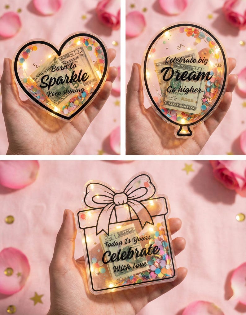 K&ouml;nnte beinhalten: Drei transparente, dekorative Geldhalter in Herz-, Ballon- und Geschenkboxform. Jedes enth&auml;lt einen US-Dollar-Schein, Konfetti und Lichterketten. Der Text lautet "Born to Sparkle", "Celebrate big Dream" und "Today Is Yours Celebrate With love".