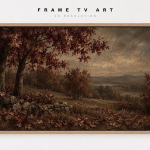 May include: A rectangular landscape painting in a light wood frame titled FRAME TV ART 4K RESOLUTION. The artwork depicts an autumn scene with dark brown trees, fallen red leaves on the ground, a stone wall, and distant rolling hills under a cloudy sky.