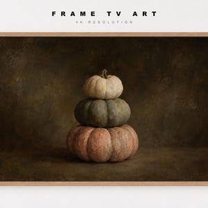 May include: A digital artwork for a frame TV featuring a stack of three pumpkins in varying sizes and muted colors, including a light cream top, a sage green middle, and a large dusty pink base, set against a dark, textured brown background.