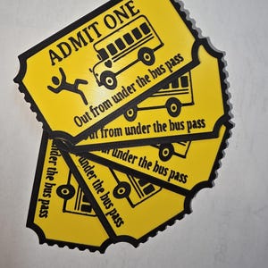 May include: Yellow tickets with black trim and text. Each ticket reads "ADMIT ONE" and features a school bus illustration. The text "Out from under the bus pass" is also printed on the tickets. A stick figure is also printed on the ticket.