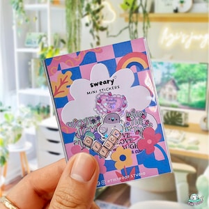 May include: A pack of "sweary" mini stickers in a clear plastic sleeve. The stickers feature various designs, including a heart with the text "Kindly Fuck Off", a bird, and the word "FUCK" spelled out with letter blocks. The background is pink and blue.