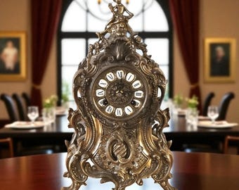 May include: An antique brass-colored mantel clock with ornate detailing. The clock features a round face with Roman numerals and a decorative figure at the top. The clock is set on a wooden table in a dining room setting.