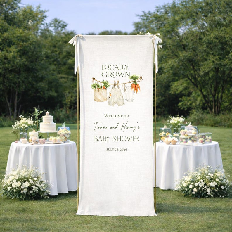 May include: A baby shower banner with the words "Locally Grown" and "Welcome to Tamara and Harry's Baby Shower" printed on it. The banner has illustrations of vegetables and baby clothes. The date of the baby shower is July 26, 2026.