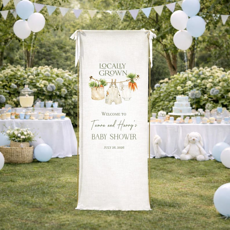 May include: A white banner with the text "Locally Grown" and "Welcome to Tamara and Harry's Baby Shower July 26, 2026." The banner has illustrations of vegetables and baby clothes. The background includes tables, balloons, and greenery.