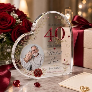 May include: A heart-shaped acrylic plaque featuring a circular photo of a couple, with the text CELEBRATING 40 Years TOGETHER, Michael & Linda, June 12, 2024, and RUBY ANNIVERSARY. The design includes gold vine accents, red hearts, and a red rose.
