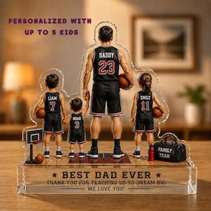 May include: A personalized acrylic basketball-themed family team display. The figures include a father wearing a jersey with "Daddy" and the number 23, and three children with their names and numbers. The base reads "Best Dad Ever".