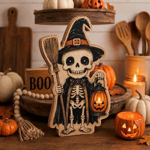 May include: A wooden cutout decoration featuring a skeleton dressed as a witch, wearing a black hat with an orange band and a black cape with a bow tie. The skeleton holds a broom in one hand and a glowing orange jack-o'-lantern lantern in the other.