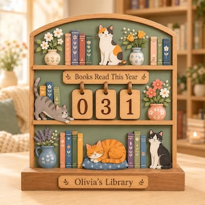 May include: A wooden bookshelf tracker with three shelves, featuring cats, flower vases, and colorful books. The top shelf has a calico cat, the middle has a counter displaying 031 with the text Books Read This Year, and the base says Olivia's Library.