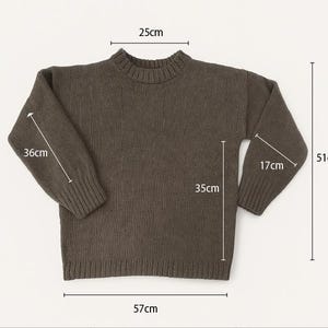 May include: A dark olive green sweater with a ribbed crew neck and cuffs. The sweater measures 22.4 inches across the chest, 14 inches from the shoulder to the hem, and 20 inches from the shoulder to the cuff. The total length is 20 inches.