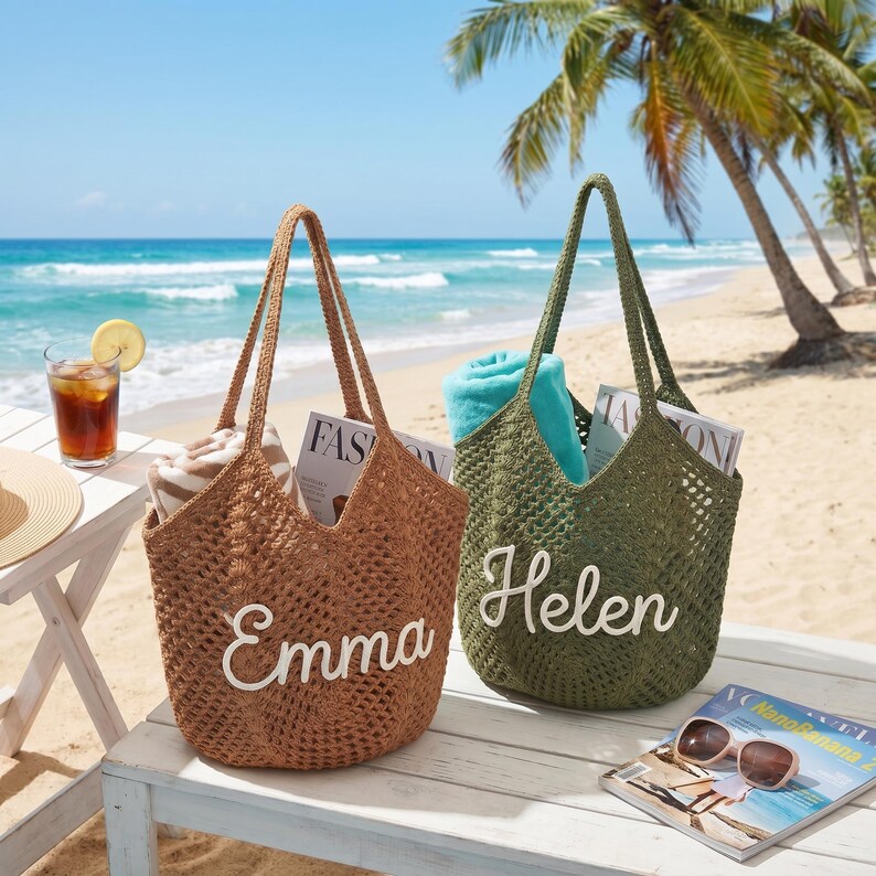 May include: Two open-weave tote bags on a beach. One is brown with the name "Emma" in white script, the other is olive green with "Helen". Both bags have long handles and are filled with magazines and towels. A drink and sunglasses are nearby.