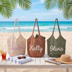 May include: Three woven tote bags in beige, brown, and olive green, each with a name embroidered on the front: Sophia, Kelly, and Olivia. The bags are on a white table with beach accessories, including a towel, sunglasses, and a straw hat.