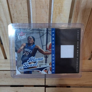 Puede incluir: Una tarjeta de intercambio de baloncesto con Alana Beard, una jugadora de los Washington Mystics. La tarjeta es de la serie Fleer Ultra e incluye un pequeño trozo de una camiseta usada en un partido.