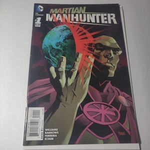 Puede incluir: Un cómic titulado "Martian Manhunter" presenta a un personaje de piel verde sosteniendo un globo azul y verde. La portada incluye el logo de DC Comics, el número 1 y el precio. El fondo es oscuro con acentos rojos y rosas.