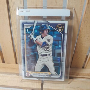 Puede incluir: Una tarjeta de béisbol con Cooper Pratt, un jugador de los Milwaukee Brewers, que lleva un uniforme blanco y azul con el número 85. La tarjeta está en una funda de plástico protectora con una etiqueta Beckett Shield.