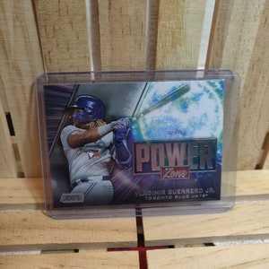 May include: A baseball card featuring Vladimir Guerrero Jr. of the Toronto Blue Jays. The card has a silver background with a blue and green power zone graphic. The card text reads "Power Zone" and "Vladimir Guerrero Jr. Toronto Blue Jays".