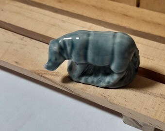 May include: A small, blue ceramic figurine of a tapir. The figurine is standing on a base and has a detailed, realistic appearance.