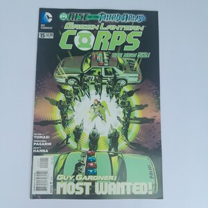 May include: A comic book cover for Green Lantern Corps #15, featuring a dynamic illustration. The cover displays the text "Rise of the Third Army" and "Guy Gardner: Most Wanted!" with a police car and figures in action. The comic is from DC Comics.