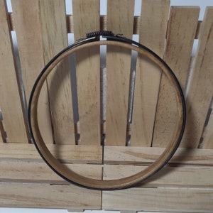 May include: A black and brown embroidery hoop with a spring-loaded closure.