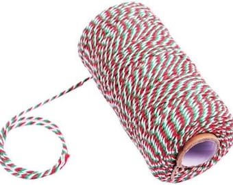 May include: A roll of red, white, and green baker's twine. The twine is wound around a cardboard tube.