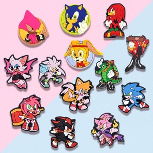 May include: A collection of colorful cartoon character charms, including Sonic the Hedgehog and other characters from the franchise. The charms are in various poses and colors, with a mix of circular and character-shaped designs.