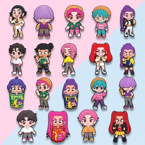 May include: A collection of colorful cartoon character charms. Each charm features a unique design with different hairstyles, outfits, and accessories. The charms are set against a pink and blue background.