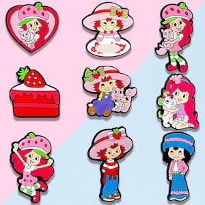 May include: A collection of colorful cartoon character charms featuring a girl with red hair and a strawberry hat. The charms include a heart-shaped design, a cake, and various poses with pets. The color palette includes pink, red, green, and blue.
