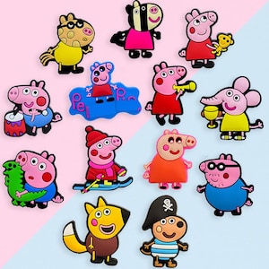 May include: A collection of colorful cartoon character magnets featuring various characters in different poses and outfits. The magnets are in various colors, including pink, yellow, red, and blue, and are arranged on a light blue and pink background.
