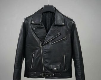 Puede incluir: Chaqueta de cuero negro con cierre de cremallera asimétrico, solapas con muescas y múltiples bolsillos con cremallera. La chaqueta tiene un cinturón en la cintura y está colgada de una percha negra. Una prenda de abrigo clásica.