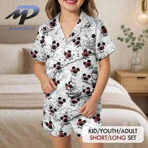 May include: White pajama set with a repeating pattern of cartoon mouse characters wearing red bandanas and eye patches. The short-sleeved top and shorts feature a nautical map design. The text "KID/YOUTH/ADULT SHORT/LONG SET" is visible.
