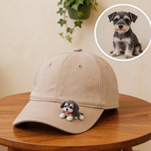 Peut inclure: Casquette de baseball beige avec une figurine de chien Schnauzer miniature attachée à l'avant. La casquette a une visière incurvée et un bouton sur le dessus. Une image circulaire d'un chien Schnauzer est en arrière-plan.
