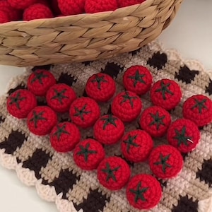 Può includere: Pomodori rossi all'uncinetto fatti a mano con cime verdi, disposti su una superficie all'uncinetto fantasia, bianco sporco e marrone. Alcuni pomodori sono in un cestino di vimini. Un oggetto affascinante e fatto a mano.