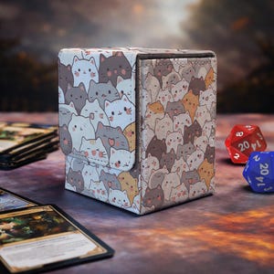 Op de afbeelding: Een rechthoekige deckbox met een herhalend patroon van cartoonkatten in tinten wit, grijs, bruin en oranje. De doos heeft een magnetische klepsluiting en een gestructureerd oppervlak, met een dichte rangschikking van kattengezichten met diverse uitdrukkingen.