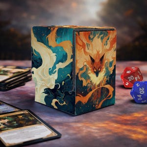 May include: A card storage box with a vibrant design featuring a fiery fox and swirling blue and orange patterns. The box is rectangular and has a magnetic closure. Two dice and several cards are visible.